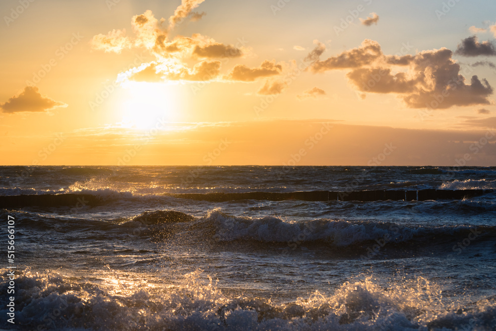 Obraz premium colored sunset with cloud cover over the sunset at the beach - dramatic sunset on the baltic sea