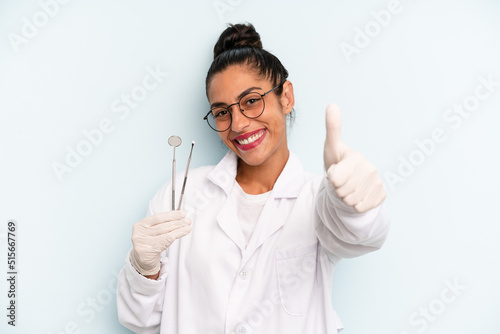 hispanic woman feeling proud,smiling positively with thumbs up. dentist concept