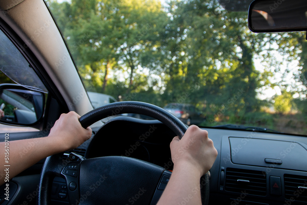 Happy teen girl sitting on driver seat in new car joyful smiling hold hands on wheel. Successful getting driver license