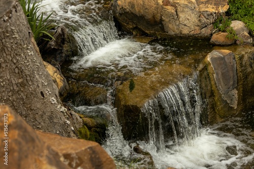 Scenic view of a cascade flowing down the rocks covered with green grass photo