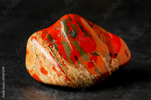 Stone mineral jasper on a black concrete background. The concept of using minerals and crystals in astrology and alternative or complementary medicine. photo