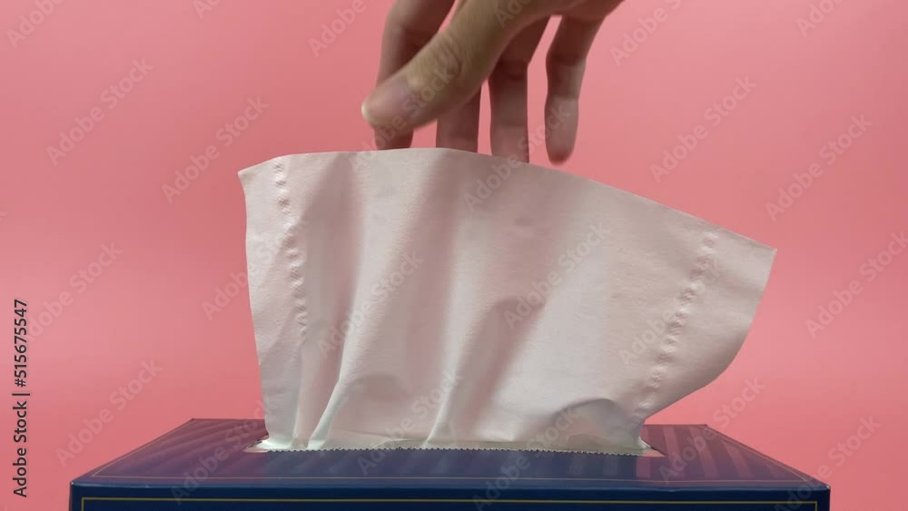 Slow motion, a person's hand pull out a piece of tissue from tissue paper box isolated on green background.