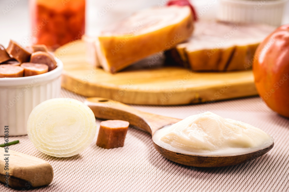 spoon of pork fat, lard used as a culinary ingredient in Brazil, pork meat in the background spoon of pork fat, lard used as a culinary ingredient in Brazil, pork meat in the background