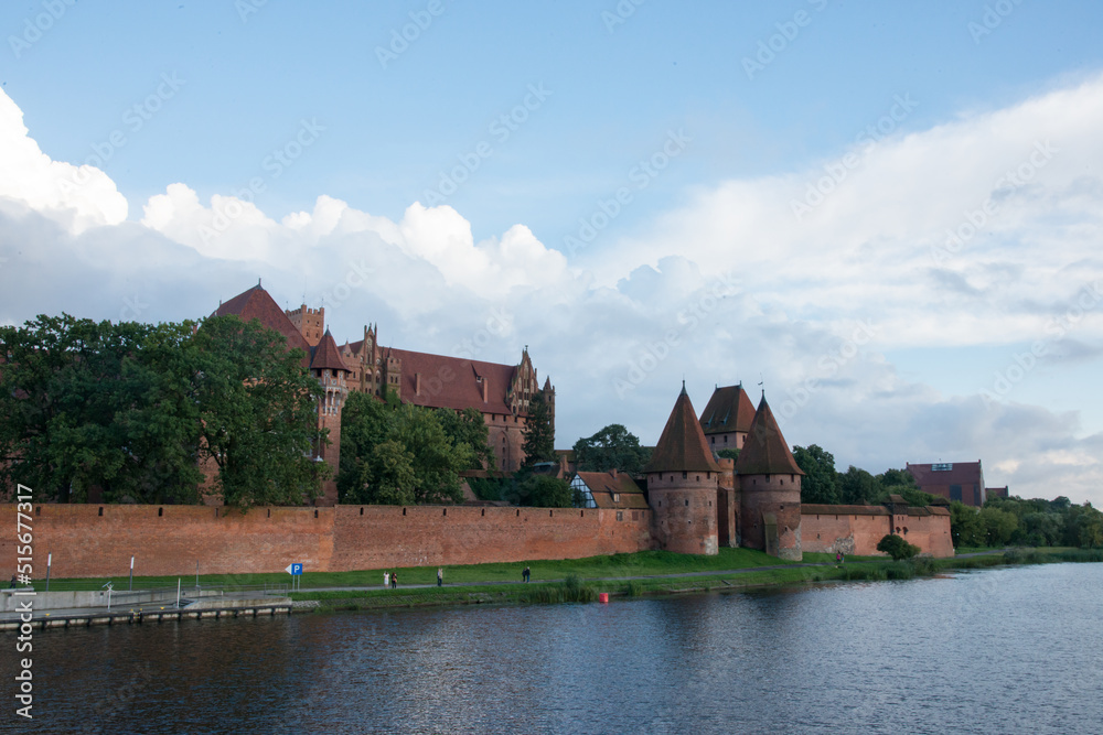 Beautiful view of Malbork castle next to the river. Fort and buildings.