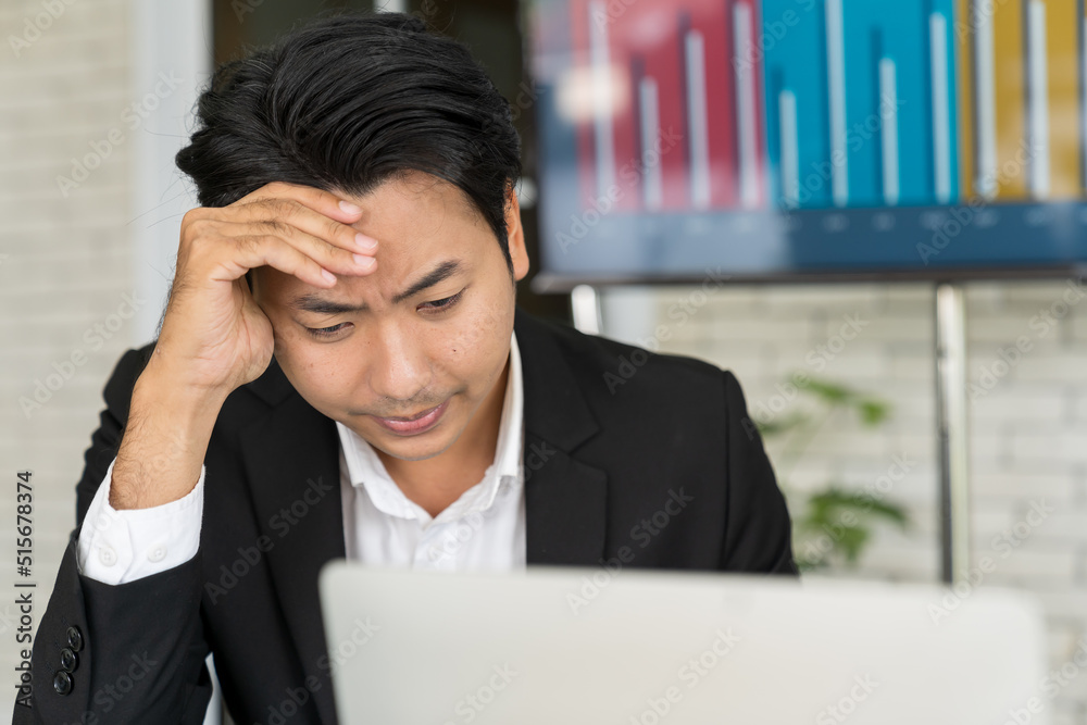 Close up of Asian businessman working with headache in the office. Stressful Asian businessman working with laptop and touching his forehead. Office syndrome concept. Close up of Asian businessman working with headache in the office. Stressful Asian businessman working with laptop and touching his forehead. Office syndrome concept.