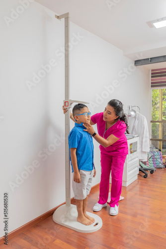 Latina pediatrician measuring a child with a wall ruler in her office