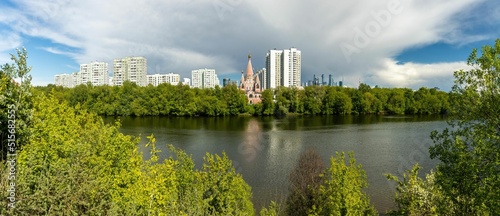 Panoramic shot of the Church of All Saints in Moscow on the shore of a river surrounded by trees photo