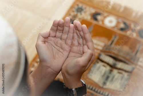 Top view of a young Muslim boy in a headscarf praying dua in a blurred background photo