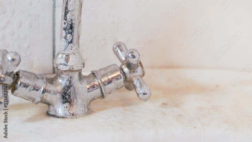 Dirty shiny washbasin faucet being sprayed with foam detergent Dirty shiny washbasin faucet being sprayed with foam detergent