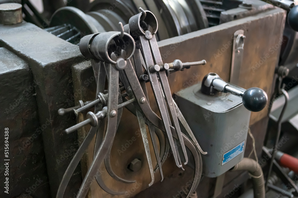 Fototapeta premium Closeup of a measuring special equipment like calipers, dividers & compass of old Lathe Machinery. Vintage Industrial Machinery in a old factory.