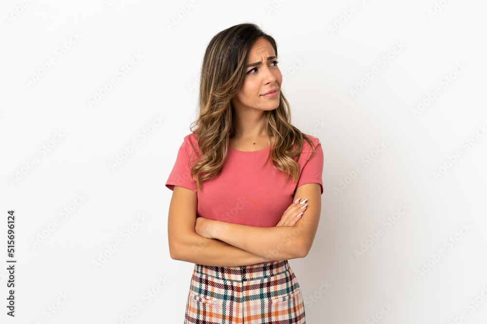 Young woman over isolated background making doubts gesture looking side Young woman over isolated background making doubts gesture looking side