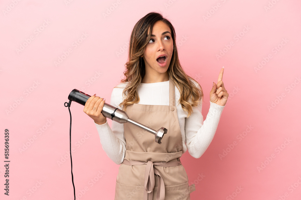 Young woman using hand blender over isolated pink background thinking an idea pointing the finger up Young woman using hand blender over isolated pink background thinking an idea pointing the finger up