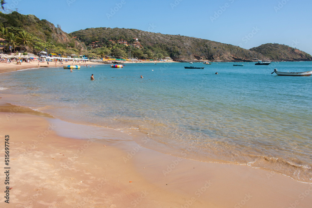 Beautiful beach of Jao Fernandez, in Buzios, Brazil, on a sunny day, surrounded by hills and blue water. 