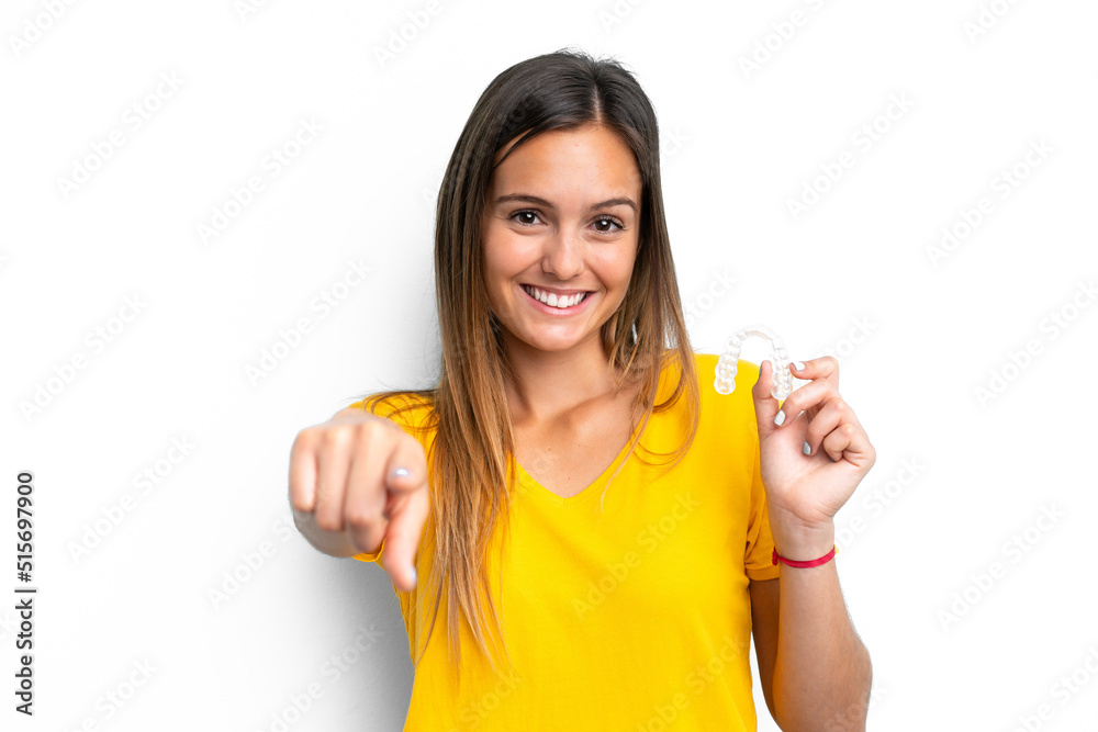 Young caucasian woman holding invisible braces isolated on white background points finger at you with a confident expression Young caucasian woman holding invisible braces isolated on white background points finger at you with a confident expression