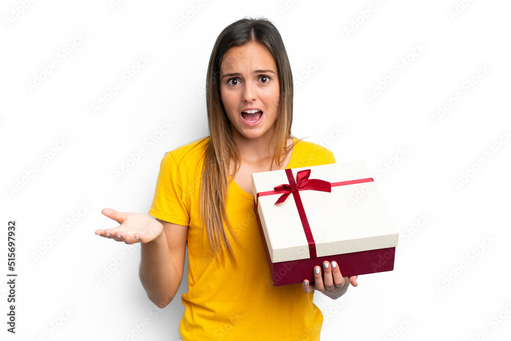 Young caucasian woman holding a gift isolated on white background with shocked facial expression Young caucasian woman holding a gift isolated on white background with shocked facial expression