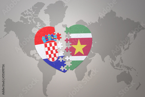puzzle heart with the national flag of croatia and suriname on a world map background.Concept.
