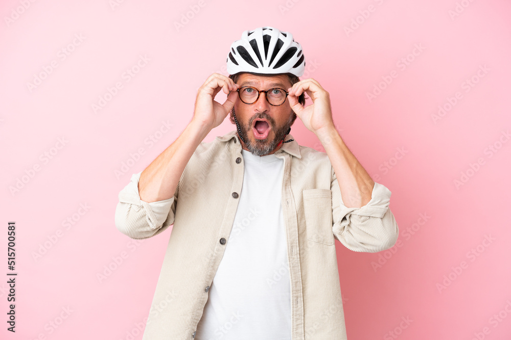 Senior dutch man with bike helmet isolated on pink background with glasses and surprised Senior dutch man with bike helmet isolated on pink background with glasses and surprised