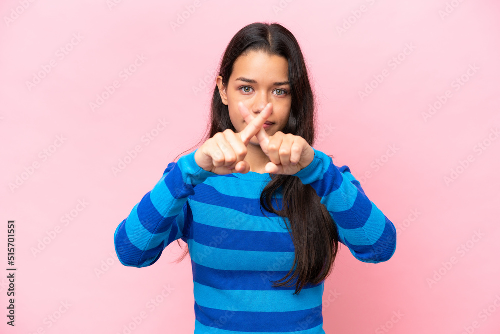 Young Colombian woman isolated on pink background making stop gesture with her hand to stop an act Young Colombian woman isolated on pink background making stop gesture with her hand to stop an act
