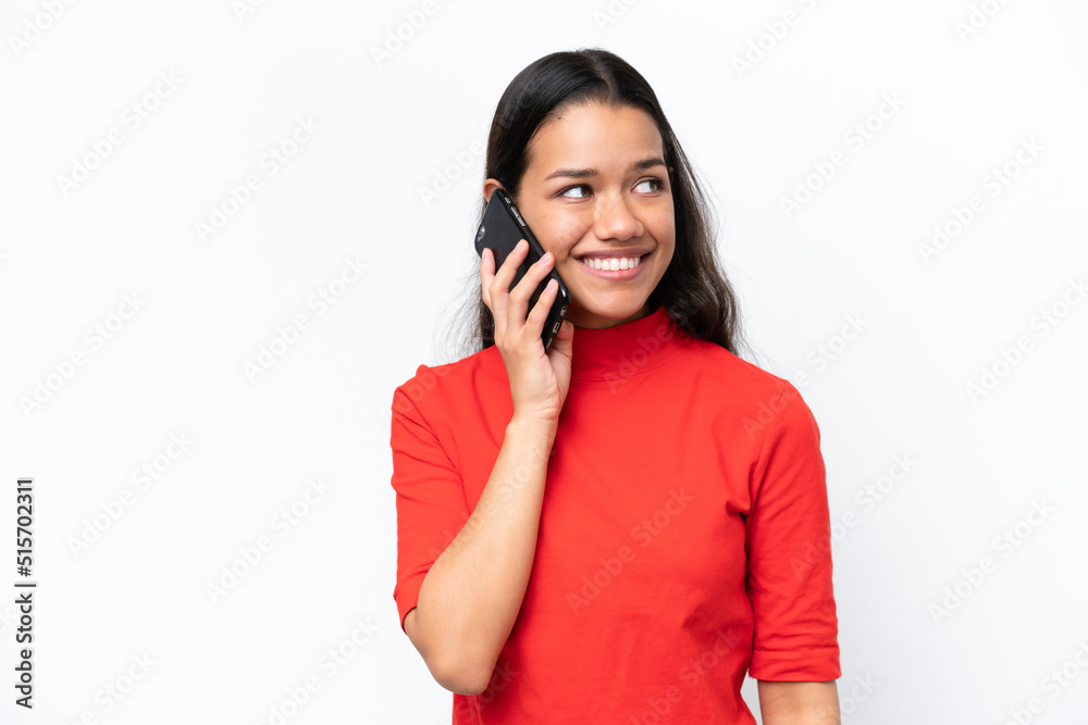 Young Colombian woman isolated on white background keeping a conversation with the mobile phone with someone Young Colombian woman isolated on white background keeping a conversation with the mobile phone with someone