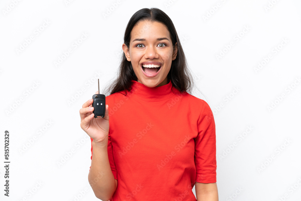 Young Colombian woman holding car keys isolated on white background with surprise and shocked facial expression Young Colombian woman holding car keys isolated on white background with surprise and shocked facial expression