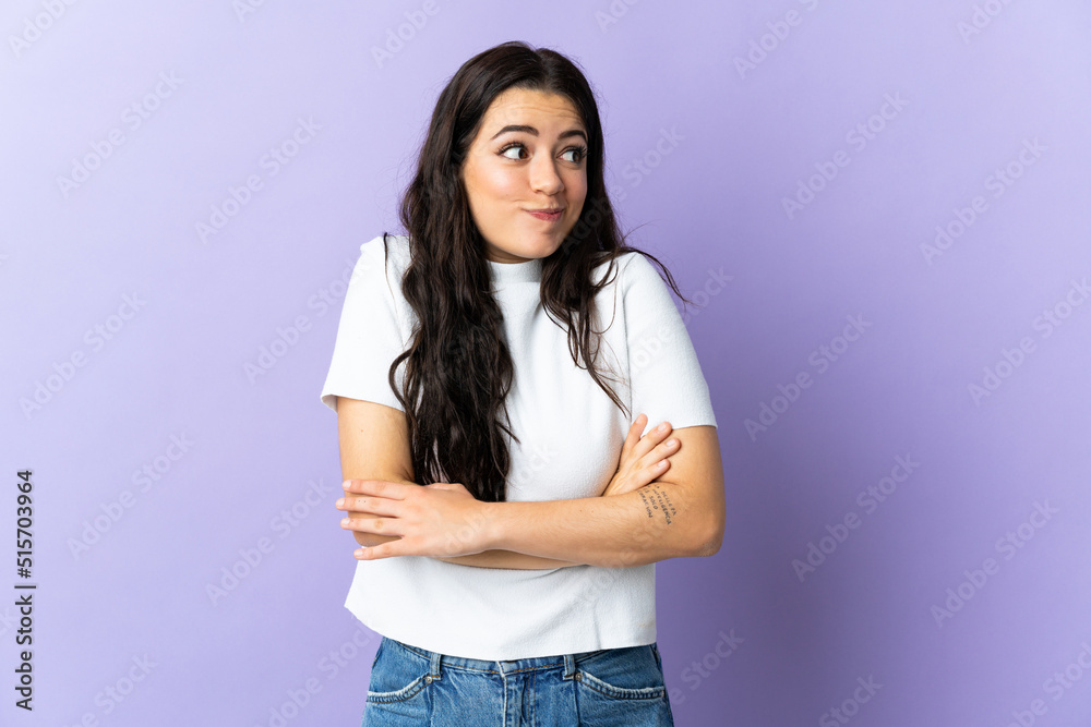 Young caucasian woman isolated on purple background making doubts gesture while lifting the shoulders Young caucasian woman isolated on purple background making doubts gesture while lifting the shoulders
