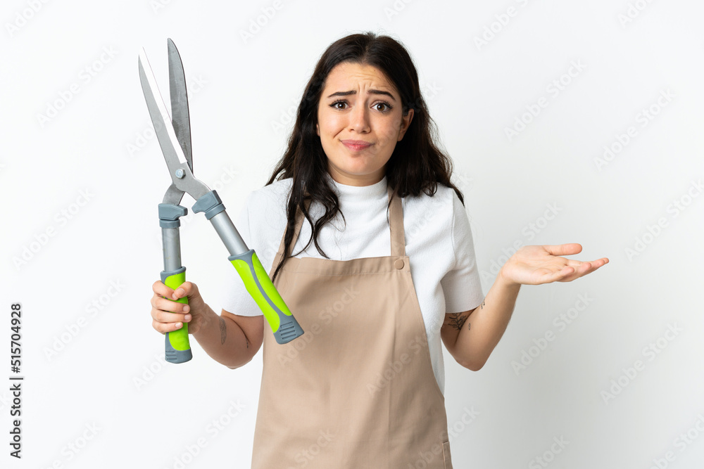 Young caucasian woman holding a plant isolated on white background having doubts while raising hands Young caucasian woman holding a plant isolated on white background having doubts while raising hands