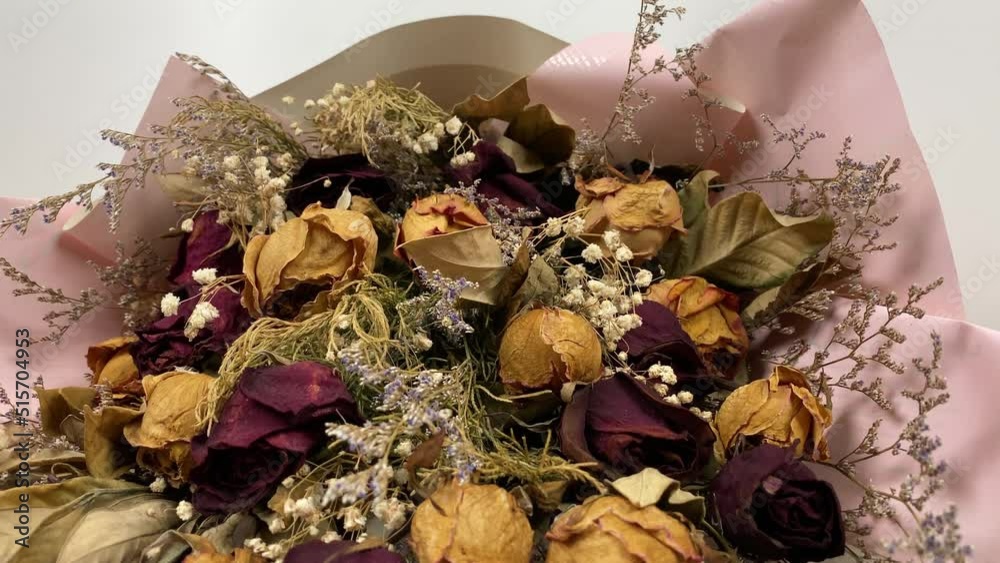 Romantic composition of dried flowers. Dried roses in slow motion on a white background. Romantic composition of dried flowers. Dried roses in slow motion on a white background.