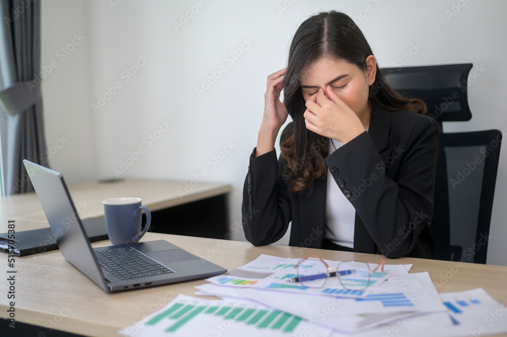 Stressed young business woman working on laptop with documents in modern office, workload concept Stressed young business woman working on laptop with documents in modern office, workload concept