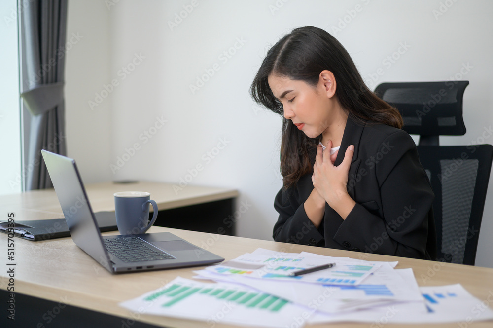 Stressed young business woman working on laptop with documents in modern office, workload concept Stressed young business woman working on laptop with documents in modern office, workload concept