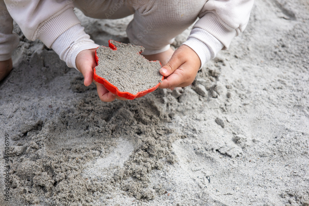 A little girl playing in the sand in the sandbox on the playground. A little girl playing in the sand in the sandbox on the playground.