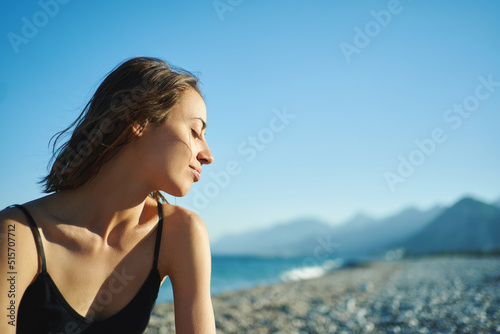Outdoor portrait beautiful summer girl enjoying weekend at beach with mountains by the sea photo