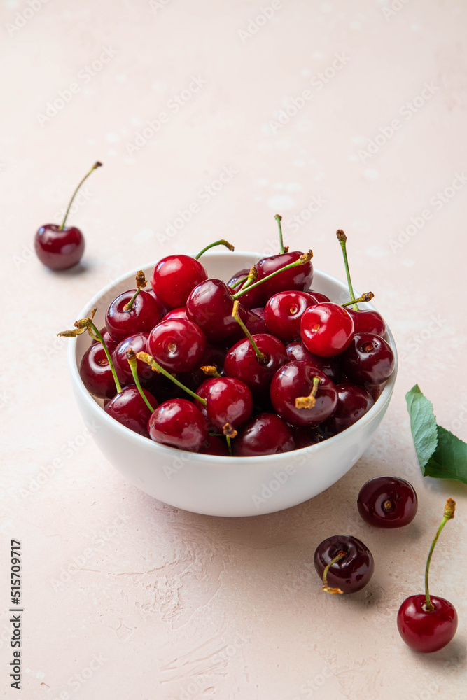 Bowl of fresh ripe cherries on pink background. Copy space for text. Selective focus. Bowl of fresh ripe cherries on pink background. Copy space for text. Selective focus.