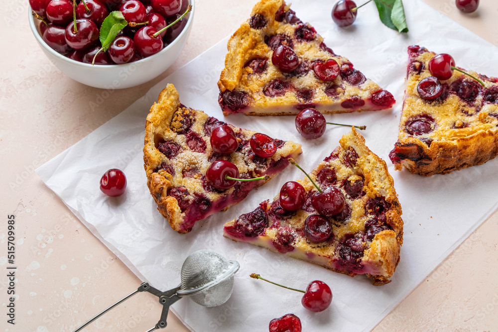 Slices of clafoutis with cherry on baking paper. Traditional homemade french cherry pie. Selective focus. Slices of clafoutis with cherry on baking paper. Traditional homemade french cherry pie. Selective focus.