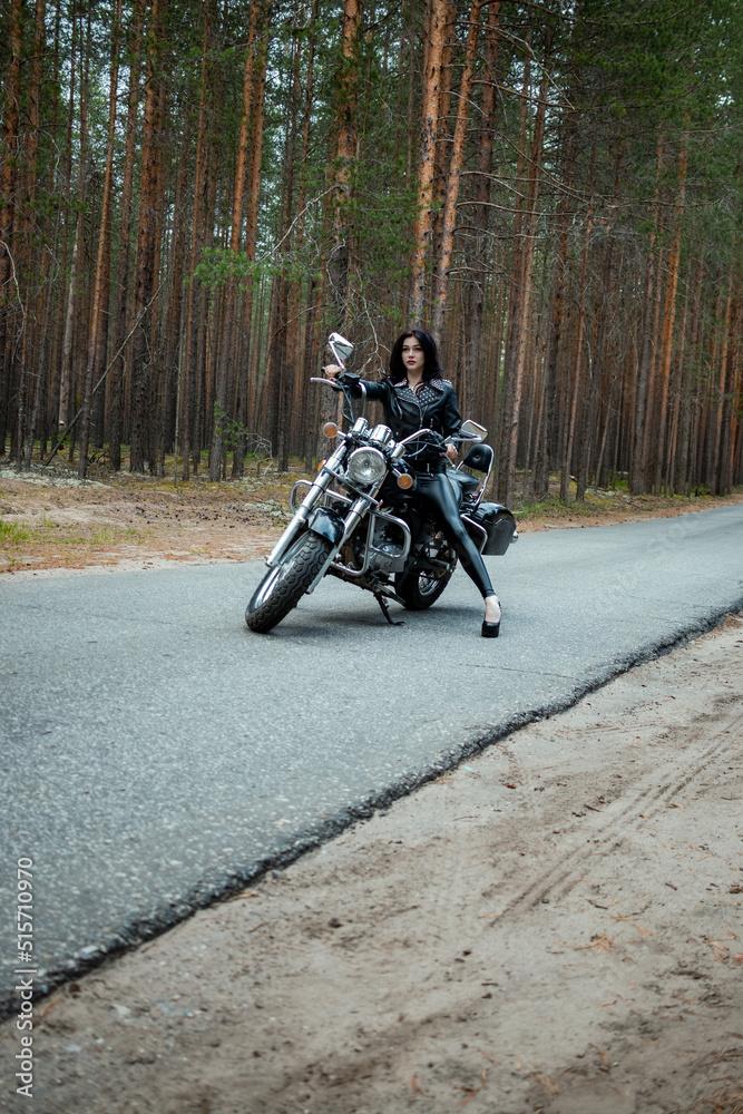 Obraz premium A girl in tight black leather sits on a motorcycle.
