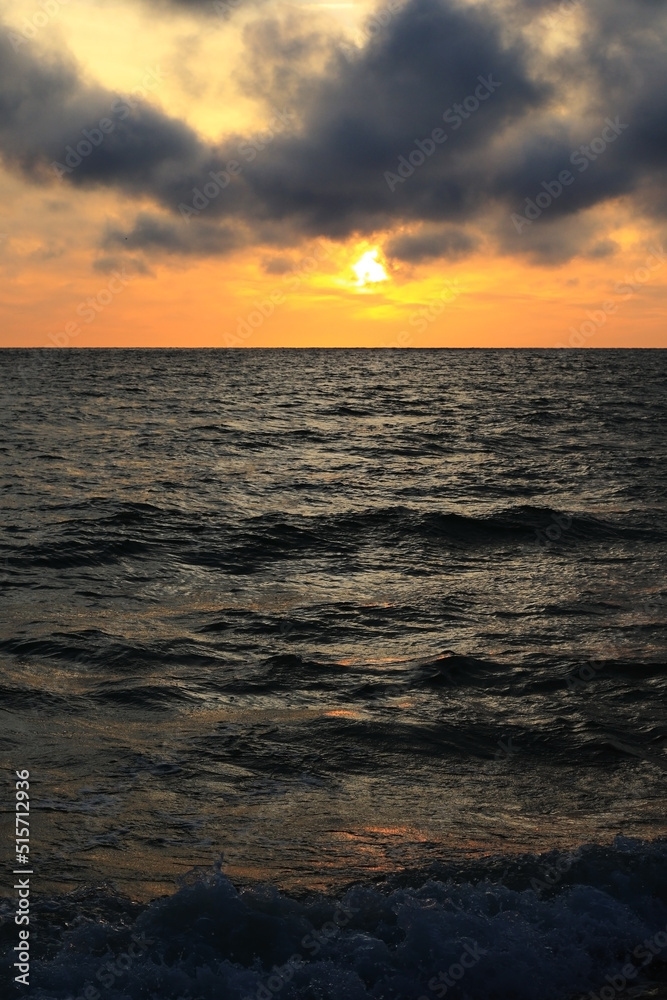 Obraz premium dark rainy cumulous clouds and epic sunset on the beach