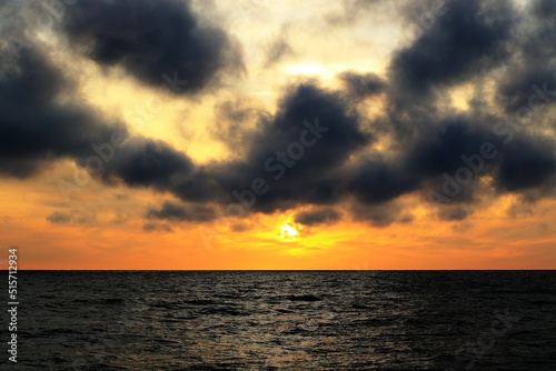 dark rainy cumulous clouds and epic sunset on the beach photo