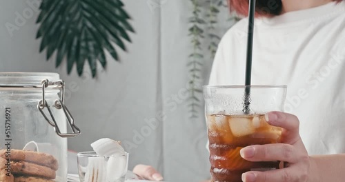 4k video, Female read book and take cup of Healthy iced coconut with black coffee from table and take a sip. Young woman in cafe or restaurant drink coconut fruit juice mixed espresso short from glass