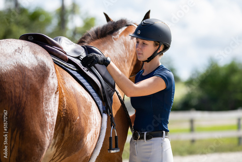 Equestrian adjusting her saddle and tack