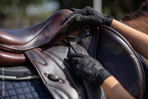 An equestrian makes adjustments to her saddle tack