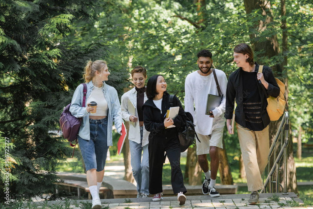 Fototapeta premium Happy asian student walking near multiethnic friends in park.