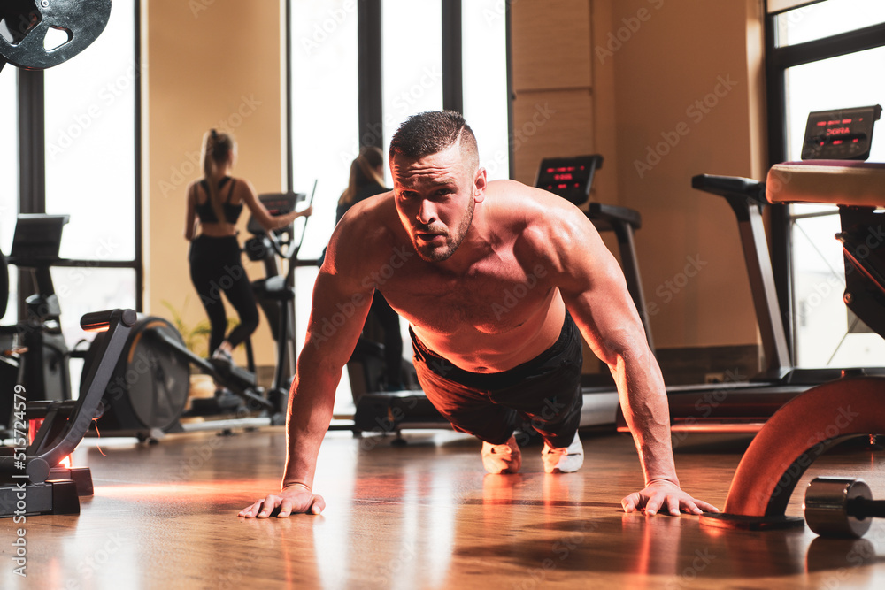 Sport man doing push ups exercise, pushup crunch. Portrait of young athlete doing exercise with dumbbell at the gym. Crossfit, sport and healthy lifestyle concept.