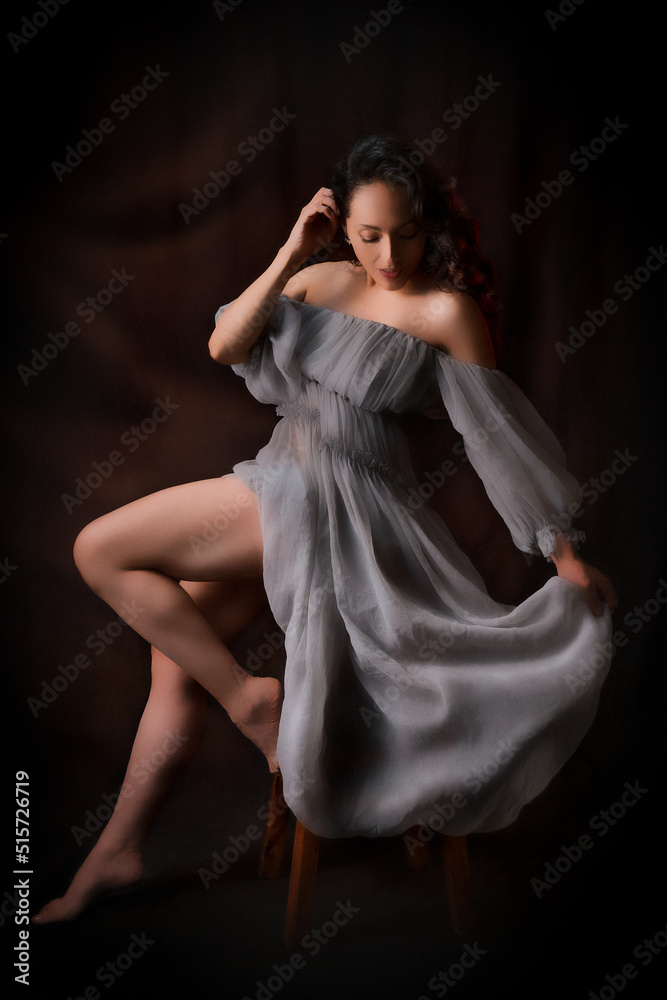 Beautiful latin woman in an antique dress, she is posing sitting she is very comfortable, low key