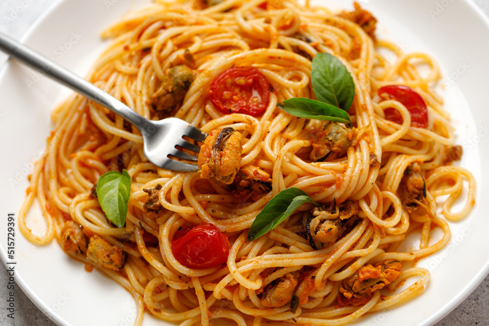 Italian seafood pasta with mussels, cherry tomatoes sauce in white plate, fork with mussel. Mediterranean food Italian seafood pasta with mussels, cherry tomatoes sauce in white plate, fork with mussel. Mediterranean food