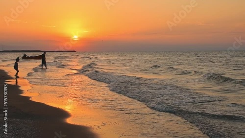 Girl play on caspian sea coast with man go swim on sunset in BAndar Anzali coast on arm summer evening photo