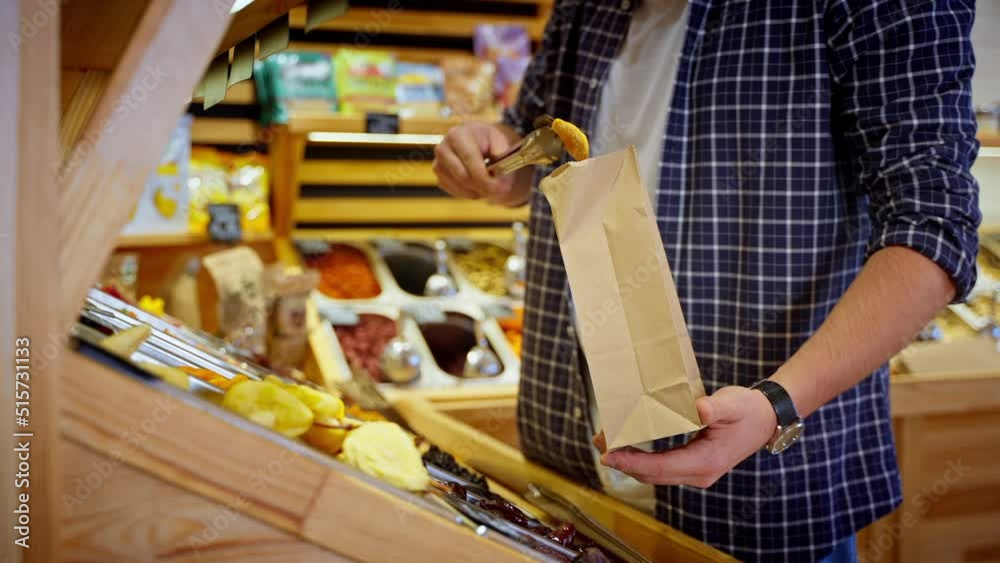 man is taking fruits secs in supermarket, buying by weight in self-service grocery