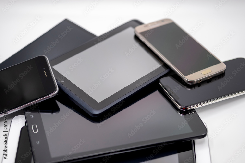 Cell phones and pads piled on white studio setup Cell phones and pads piled on white studio setup