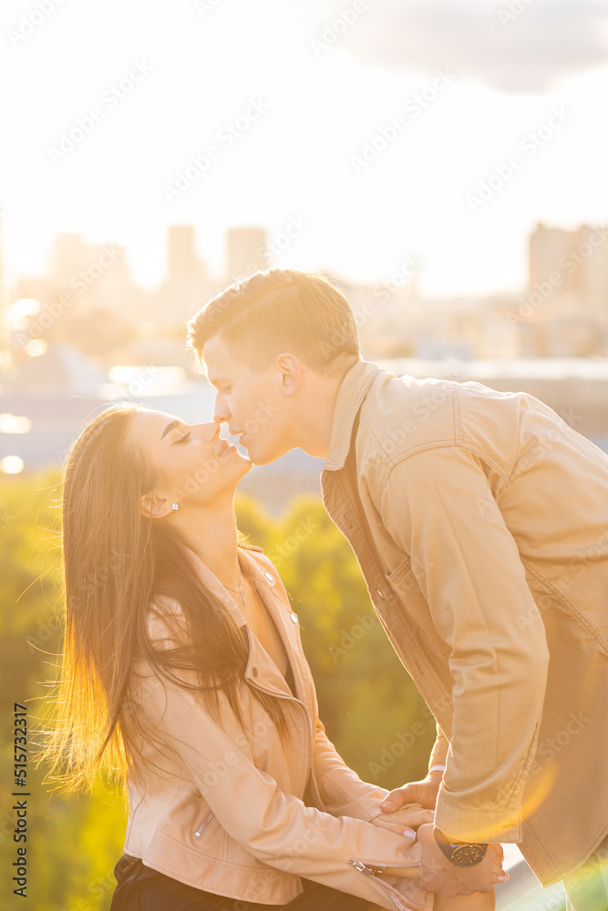 Beautiful happy young loving couple on a surprise date on a Saint Valentine's Day. Romantic date on the rooftop, summertime. Young man and beautiful girl. Newlyweds on honeymoon. Golden hour Beautiful happy young loving couple on a surprise date on a Saint Valentine's Day. Romantic date on the rooftop, summertime. Young man and beautiful girl. Newlyweds on honeymoon. Golden hour
