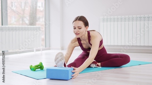 a beautiful and athletic girl in a burgundy tracksuit does exercises on the mat