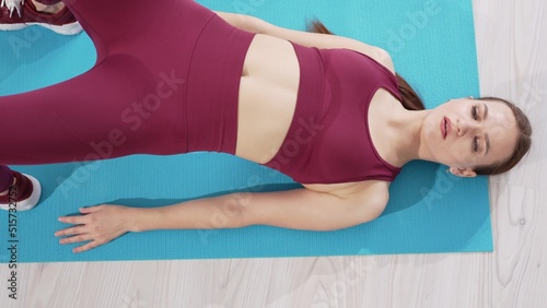 a beautiful and athletic girl in a burgundy tracksuit does exercises for stretching muscles
