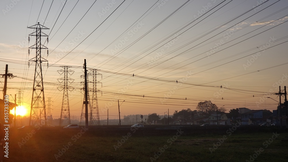 Large utility power line towers in the foreground and sunset in the background